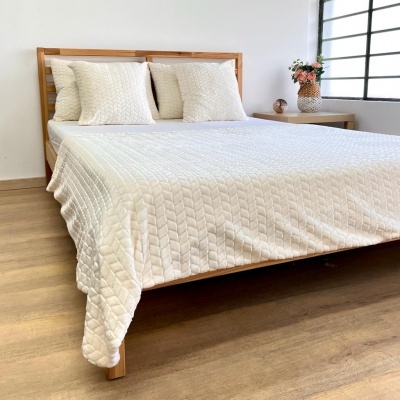 Cama de madeira com colcha e almofadas brancas texturizadas em quarto minimalista