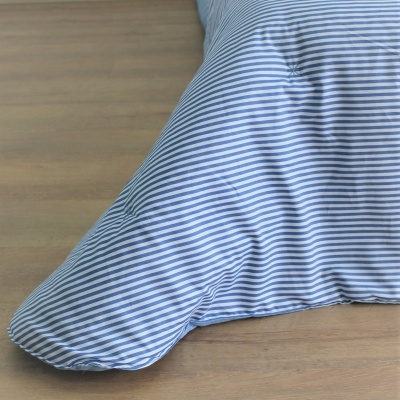 Almofada listrada azul e branca sobre madeira clara