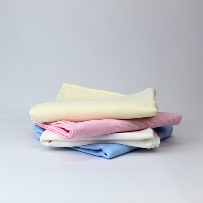 Conjunto de quatro toalhas dobradas de cores pastel sobre fundo cinza claro