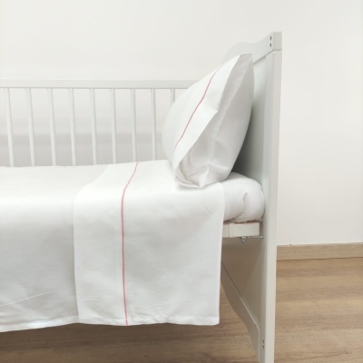 Cama com lençóis brancos com linha vermelha e estrutura de madeira branca