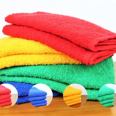 Toalhas coloridas vermelho, amarelo e verde empilhadas sobre madeira com detalhes de textura