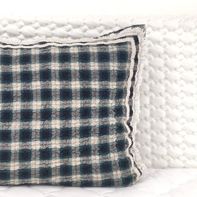 Almofada quadrada xadrez azul e branca com borda em fundo branco texturado