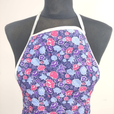 Avental floral roxo com bordas e alças brancas em manequim preto