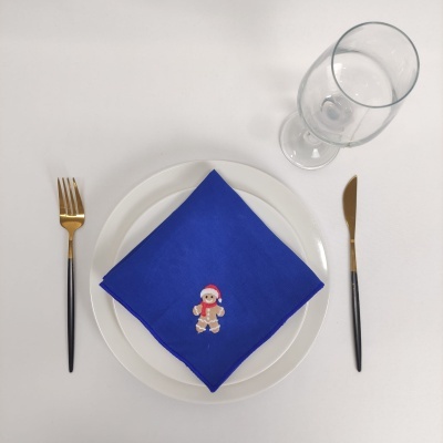 Conjunto de talheres, prato branco, guardanapo azul com boneco de gengibre bordado e copo transparente