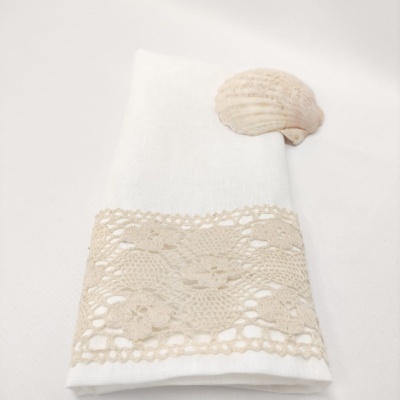 Guardanapo branco com detalhe em renda bege e concha decorativa clara
