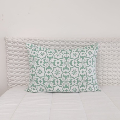 Almofada verde e branca sobre cama branca com cabeceira texturizada