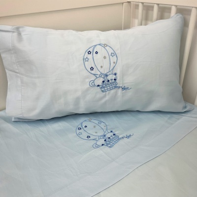 Frontal de lençol e fronha azul claro com bordado de balão de ar quente e ursinho azul