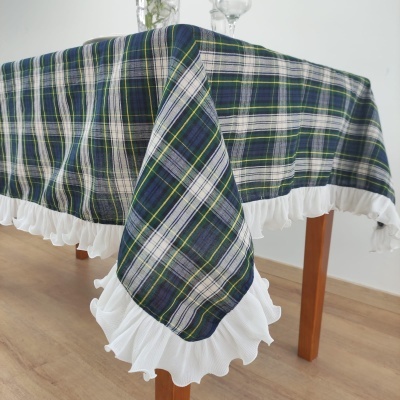 Toalha de mesa xadrez azul e branco com babado branco em mesa de madeira