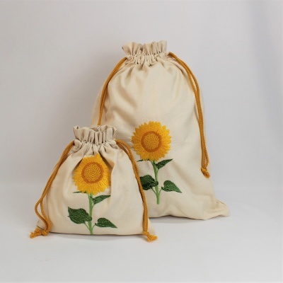 Dois sacos de pano creme com cordão laranja e estampa bordada de girassol