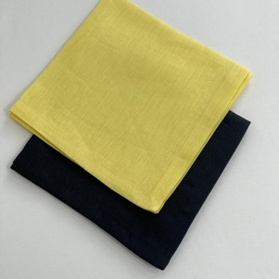 Dois lenços quadrados dobrados amarelo e azul escuro sobre superfície branca