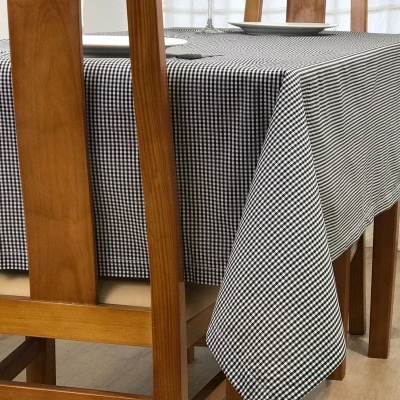 Mesa de madeira com toalha xadrez preto e branco e duas cadeiras em ambiente interior