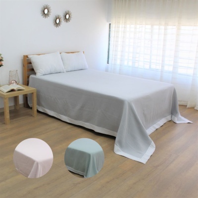 Cama de casal com colcha cinzenta em quarto minimalista com cortinas brancas e mesa de cabeceira