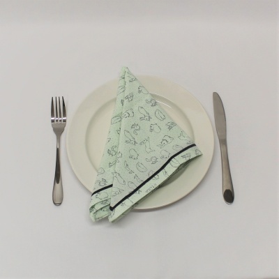 Prato branco com guardanapo verde claro com padrões de coelhos, garfo e faca ao lado