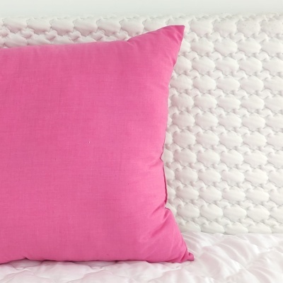 Almofada cor-de-rosa numa cama branca acolchoada