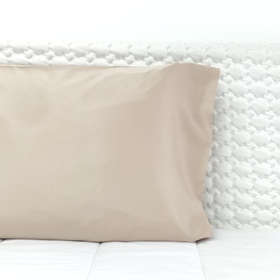Travesseiro bege sobre colchão branco com colcha texturizada branca