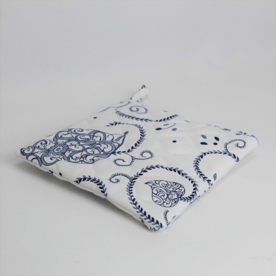 Almofada ou porta-panela branco com padrão azul em corações e arabescos