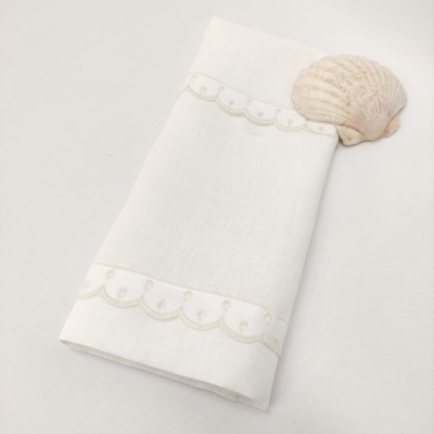 Guardanapo branco com bordado e concha ao lado