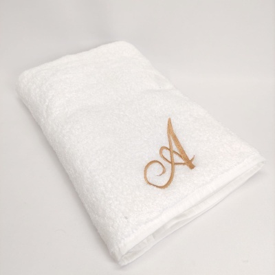 toalha branca de algodão com bordado dourado letra A
