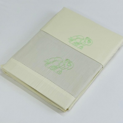 Jogo de cama branco com faixa cinza e bordados verdes de tartarugas