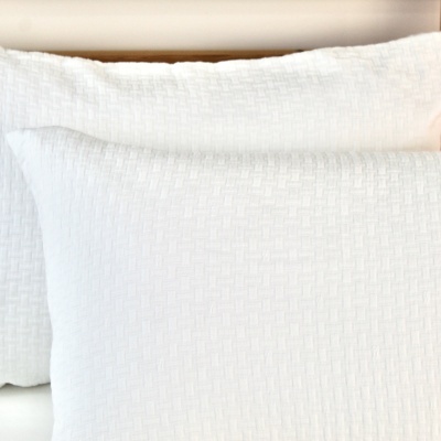 Três almofadas brancas com padrão de xadrez em relevo colocadas