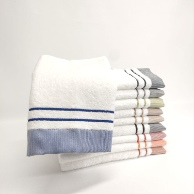 Toalhas de banho de algodão com listra azul e bainha listrada, empilhadas em várias cores.