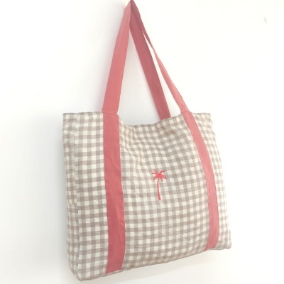 Saco de tecido xadrez bege e branco com alças rosa e bordado de palmeira