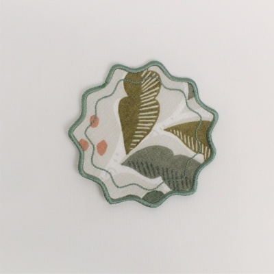 Aplicação bordada em forma de flor com padrão de folhas em verdes, castanho e rosa