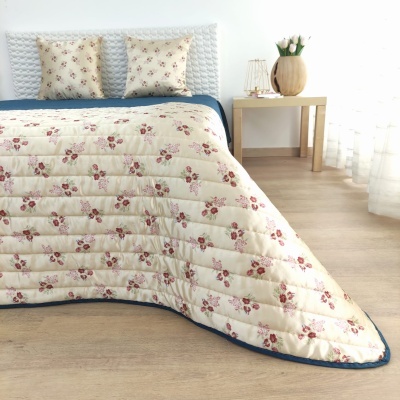 Colcha creme floral matelassê com almofadas e mesa de cabeceira