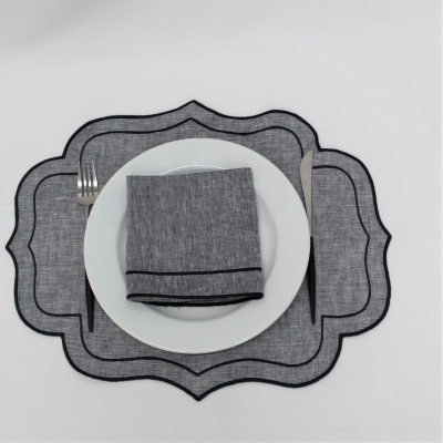 base de mesa cinzenta com linhas pretas, prato branco e guardanapo cinzento