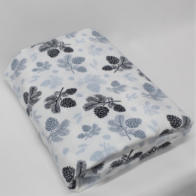 Manta branca com padrão de pinhas e folhas em preto e cinzento dobrada