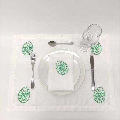 Jogo americano e guardanapo brancos com padrão verde de folha e talheres e copo