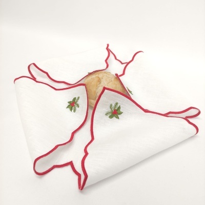 Guardanapo branco com borda vermelha e bordado verde e vermelho dobrado com pão