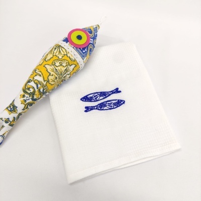 Toalha branca com peixes azuis e peixe decorativo colorido em fundo branco
