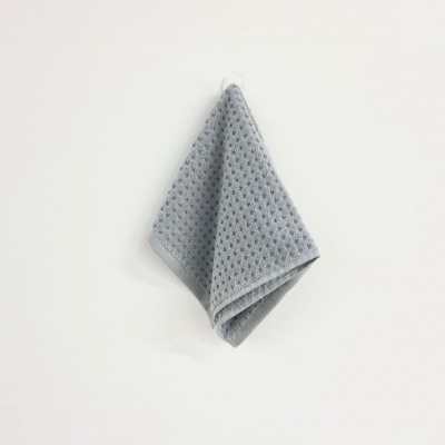 Toalha de mão cinzenta texturizada pendurada numa parede branca