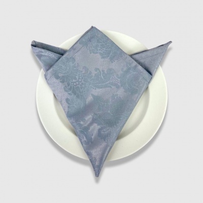 Guardanapo azul com padrão floral numa dobra sobre prato branco