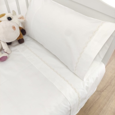 Cama de criança com roupa de cama branca e peluche de vaca