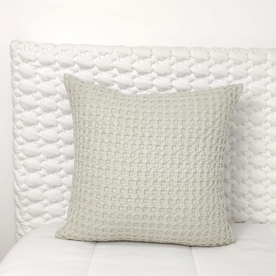 Almofada cinza claro com padrão texturizado sobre superfície branca estofada.