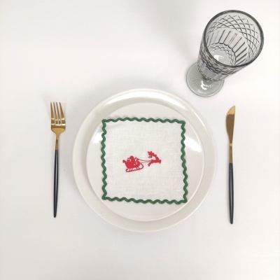 Prato branco com guardanapo bordado, talheres preto e dourado e copo de vidro relevo