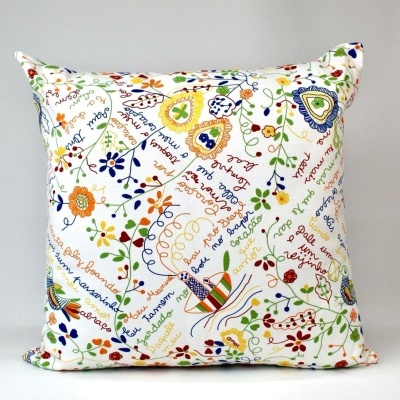 Almofada quadrada branca com padrão colorido de flores e escrita artística