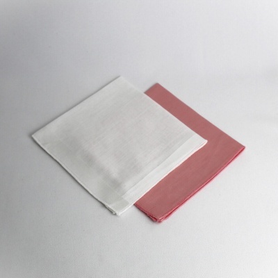 Dois lenços quadrados, um branco e um rosa, sobre fundo branco