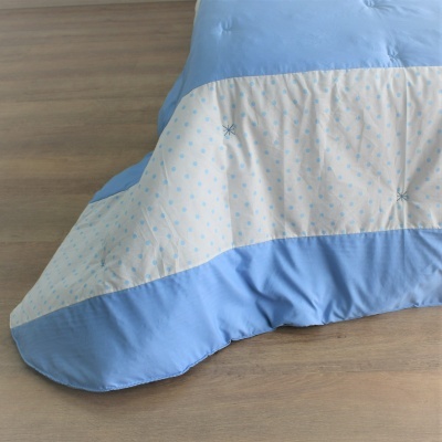 Cobertor azul e branco com padrão de bolinhas azuis sobre chão de madeira