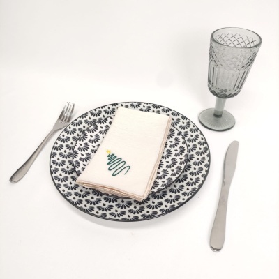 Conjunto de louça com prato decorado, guardanapo bordado, taça de vidro e talheres