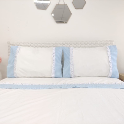 Jogo de cama com fronhas brancas e azuis com bordado em renda com espelhos hexagonais na parede