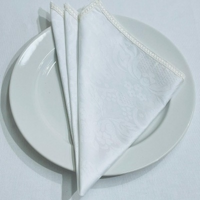 Guardanapo branco de tecido com padrão floral sobre prato branco