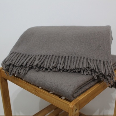 Cobertores cinzentos com franjas sobre banco de madeira