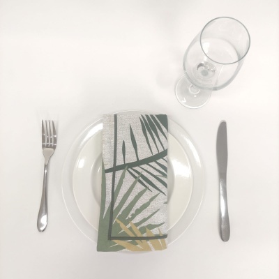 Conjunto de jantar com prato, guardanapo estampado, talheres e copo de vinho sobre mesa branca