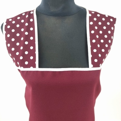 Vestido sem mangas vermelho vinho com bolinhas brancas na parte superior em manequim preto.