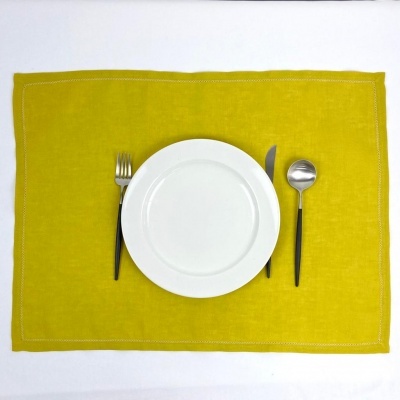 Conjunto de refeição com prato branco, talheres com cabos pretos sobre individual amarelo