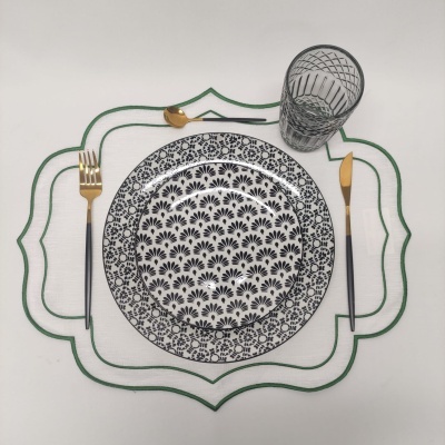 Conjunto de jantar com pratos em cerâmica preto e branco, talheres dourados e copo transparente com padrão preto