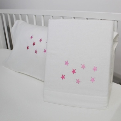 Toalhas brancas com estrelas rosa sobre berço branco